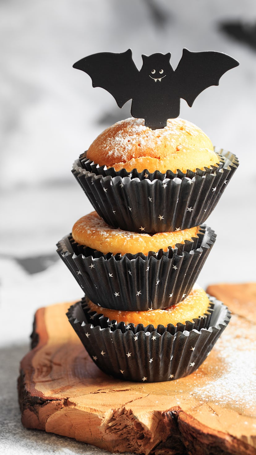 Halloween cupcakes in black capsules decorated with cardboard bats.