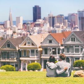 San Francisco - Alamo Square people. Couple tourists relaxing in Alamo Park by the Painted Ladies ho...