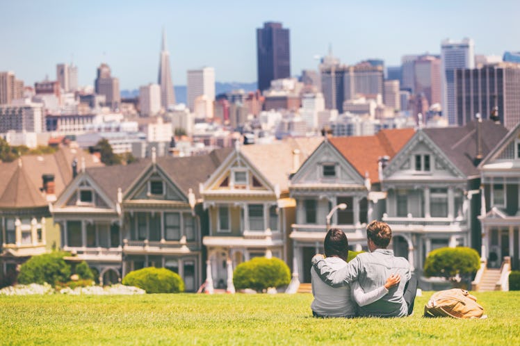 San Francisco - Alamo Square people. Couple tourists relaxing in Alamo Park by the Painted Ladies ho...