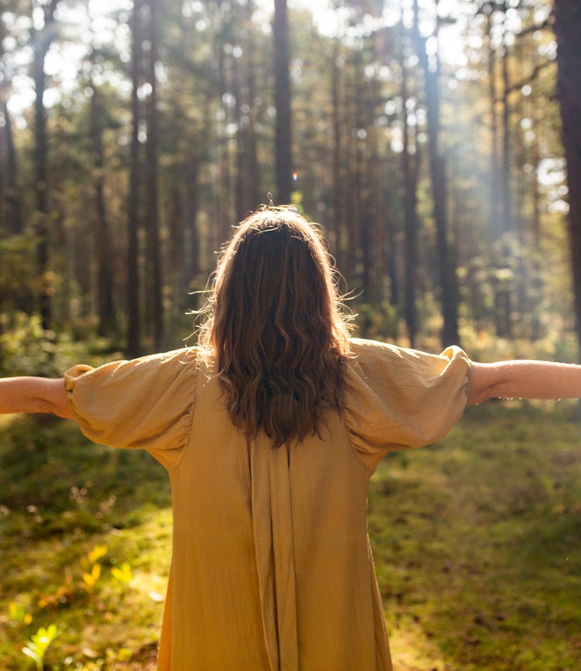 nature, spirituality and supernatural concept - young woman or witch performing magic ritual in fore...