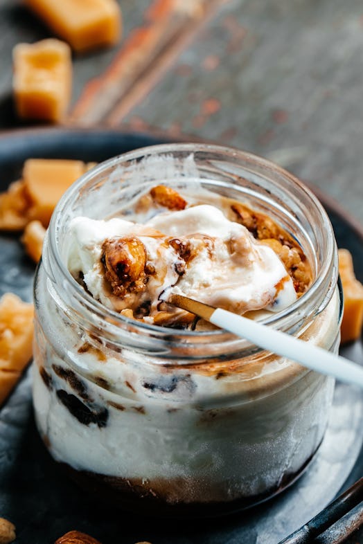 Jar with caramel ice cream served with hazelnuts in a glass jar on a blue tray, place for text.