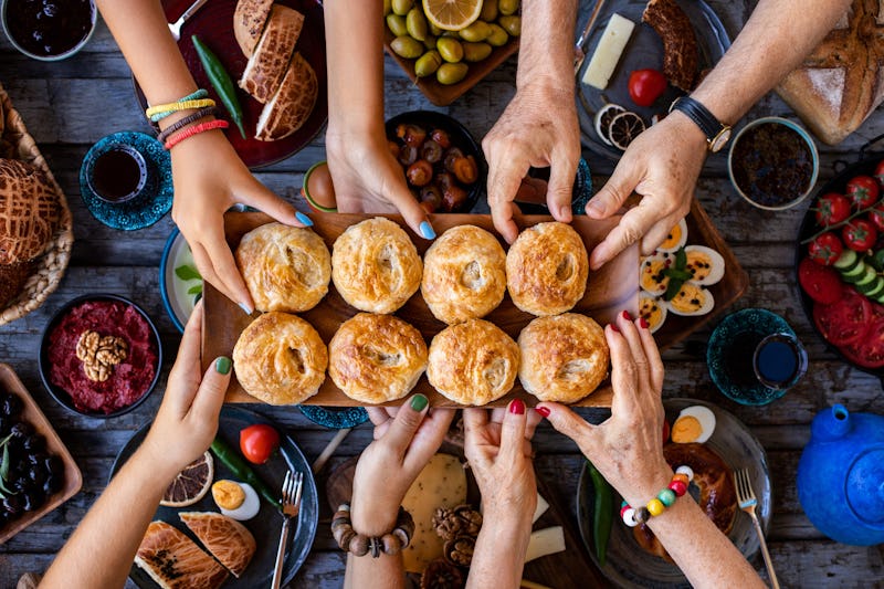 Hands taking store-bought bread rolls that taste homemade from a Thanksgiving dinner table