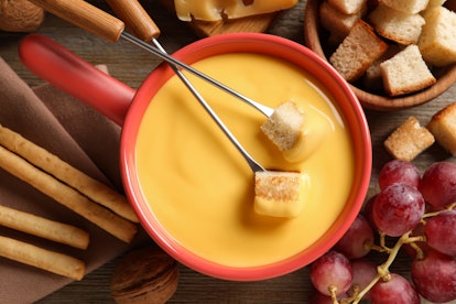 Pot of tasty cheese fondue and snacks on wooden table, flat lay