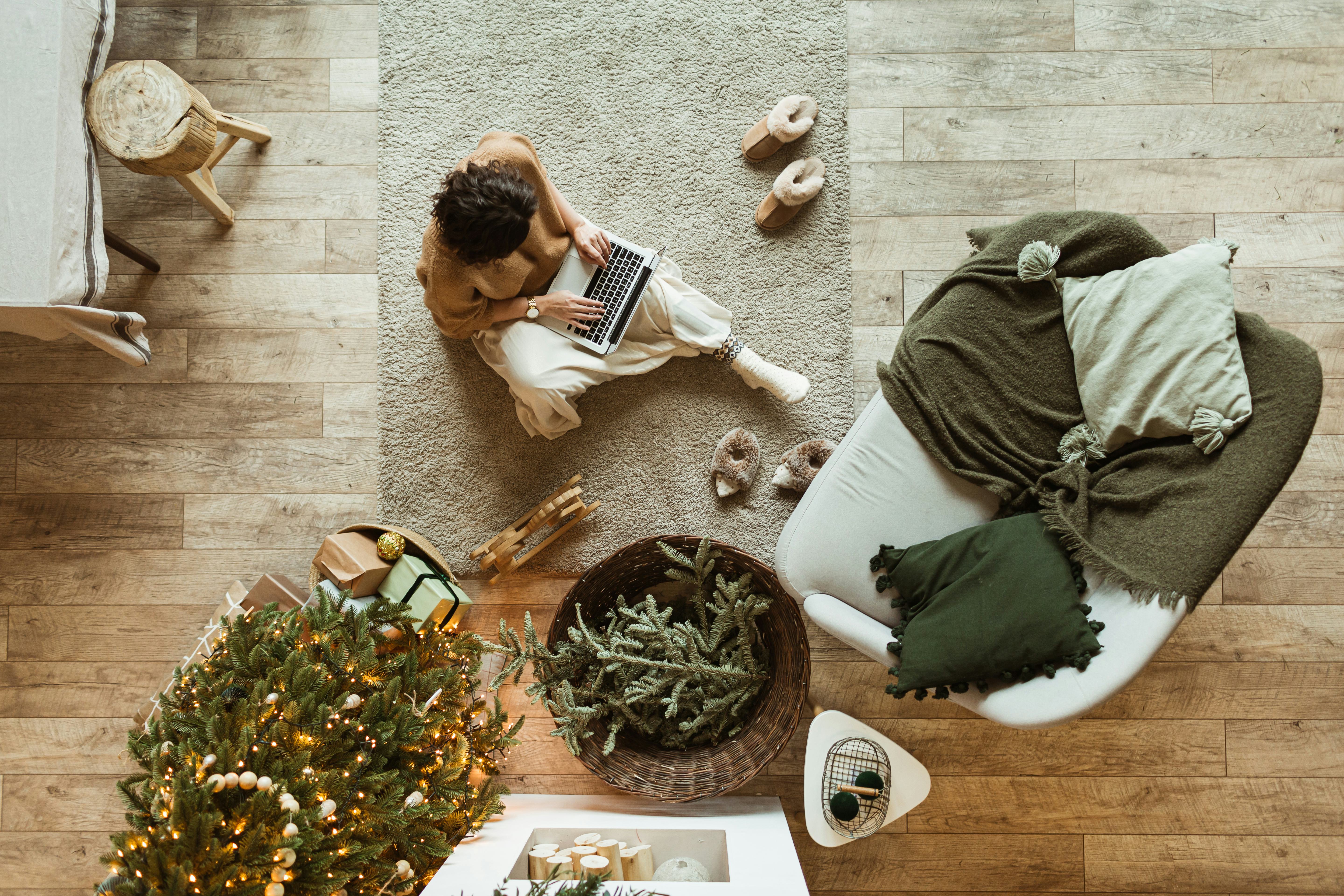 Christmas / New Year decorated home living room. Beautiful woman working on laptop. Decorated Christ...