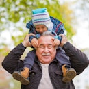 Shot of a happy senior man smiling looking away his grandson hugging him from behind copyspace relax...