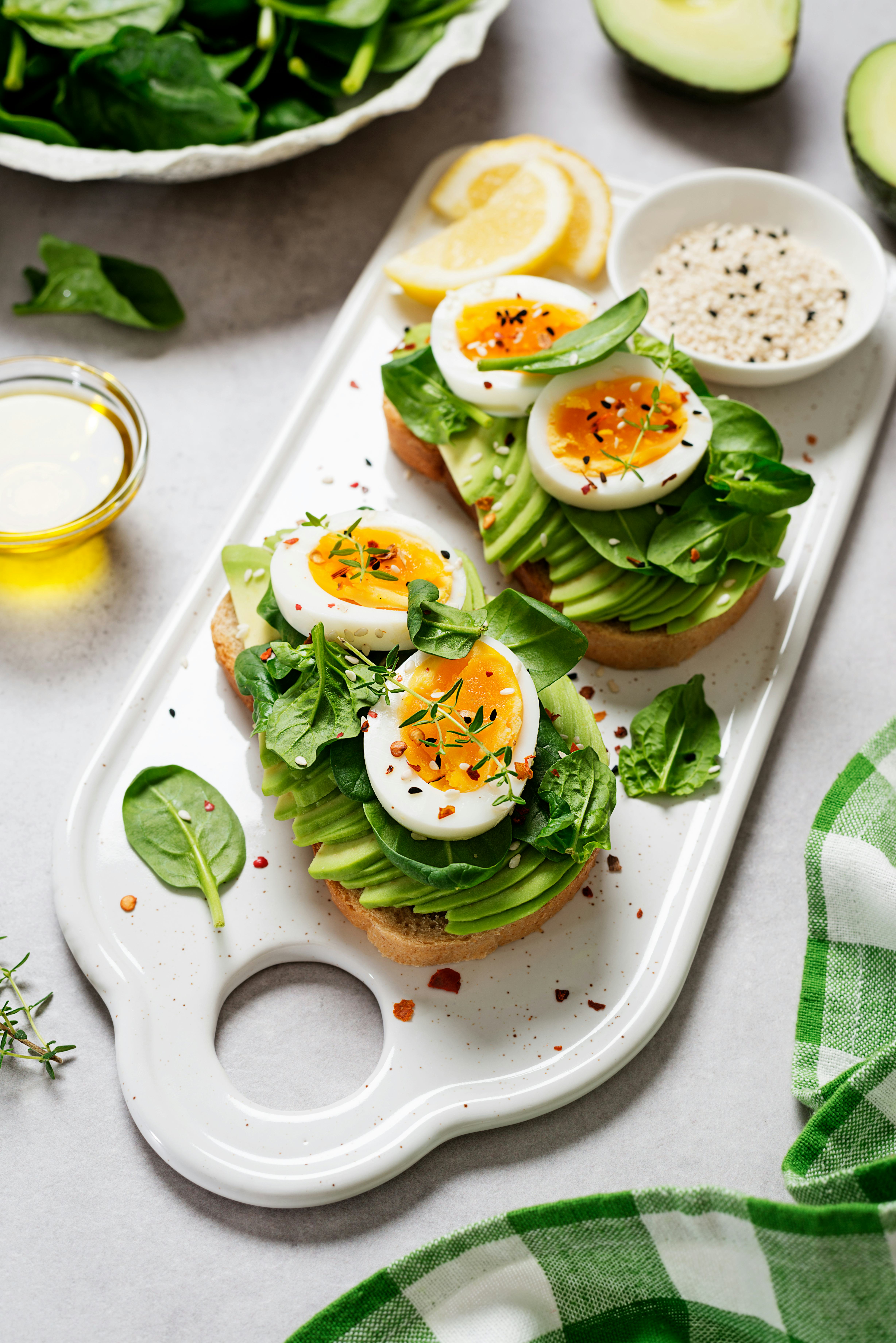 Healthy toast with sliced avocado, boiled eggs, spices and fresh spinach. Delicious breakfast or sna...