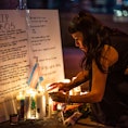 People light up candles at a makeshift memorial for the victims of Saturday's fatal shooting at Club...