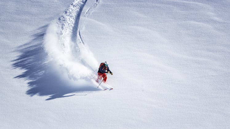 Free ride skier skiing down through fresh powder viewed from far away