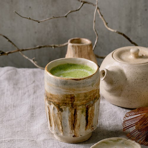 Traditional japanese hot green frothy tea matcha latte in handmade ceramic cup, powdered matcha, tea...