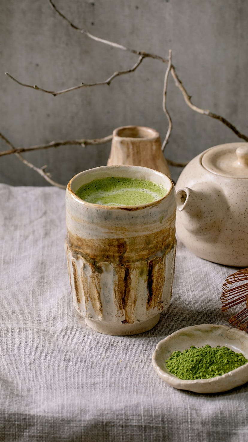 Traditional japanese hot green frothy tea matcha latte in handmade ceramic cup, powdered matcha, tea...