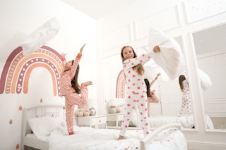 Cute little girls in pajamas playing on bed at home. Happy childhood