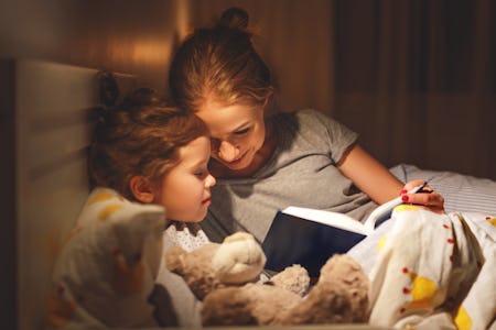 mother and child daughter reading book in bed before going to sleep