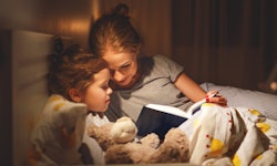 mother and child daughter reading book in bed before going to sleep 