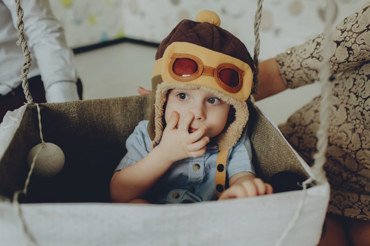 Happy kid playing and picking his nose in handmade hot air balloon basket.