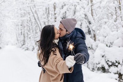A couple kissing in the snow for winter wonderland instagram captions.