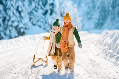 Two little kids have fun in the snow for winter instagram captions.