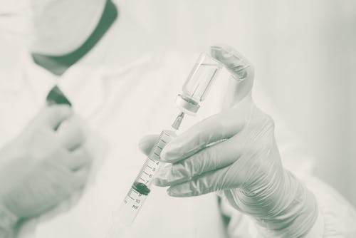 A doctor or scientist in the COVID-19 medical vaccine research and development laboratory holds a sy...