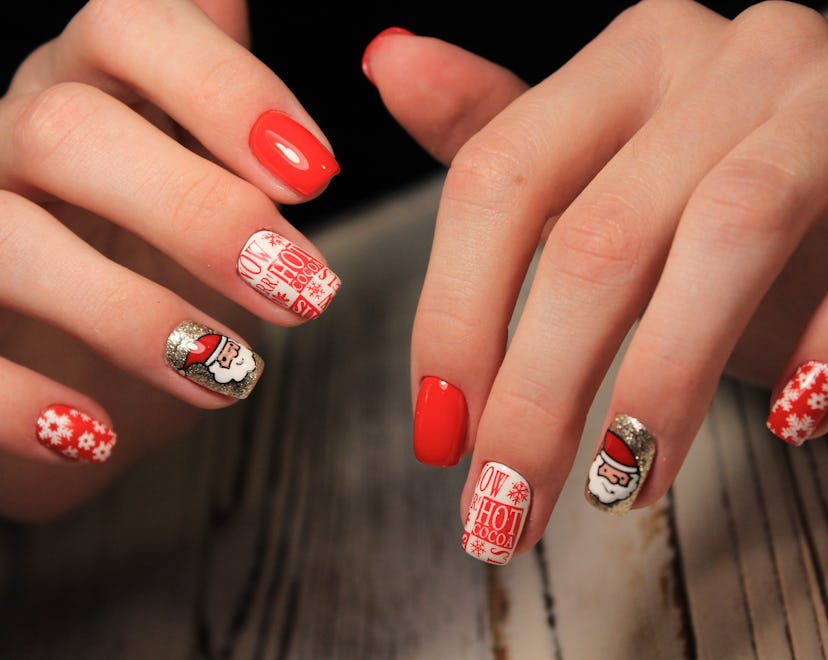 A Christmas nail art design with Santa, silver details, snowflakes, and hot cocoa stickers.