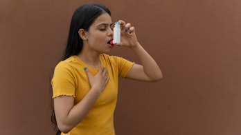 Asthmatic patient catching inhaler having an asthma attack. Young woman having asthma, chronic obstr...
