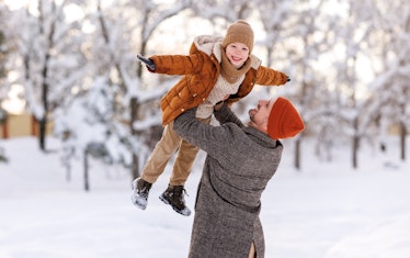 Father lifting little son up while having fun together outdoor on frosty day, happy dad and kid play...
