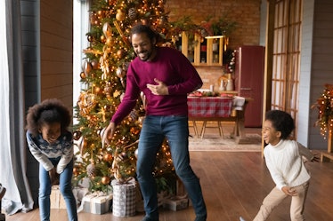 Overjoyed African American father with adorable kids having fun on winter holidays, happy family wit...