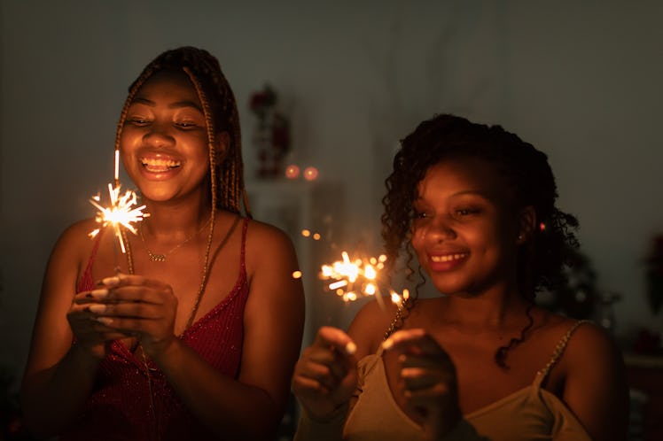 two young women holding sparklers and thinking of their new year's eve horoscopes