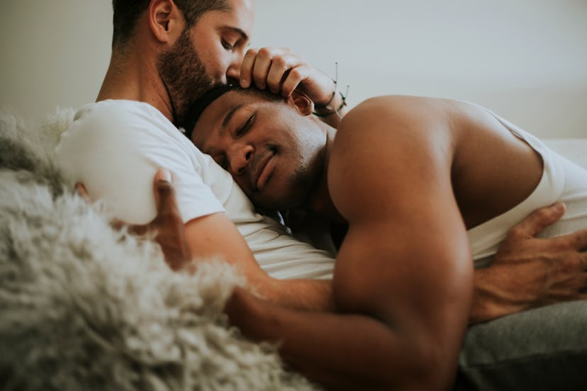 Gay couple cuddling in bed in article about sexy questions to ask your partner
