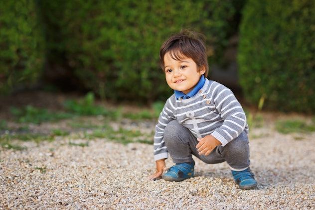 A toddler crouches down and plays with pebbles. Boy names that start with J include Jamal, which mea...