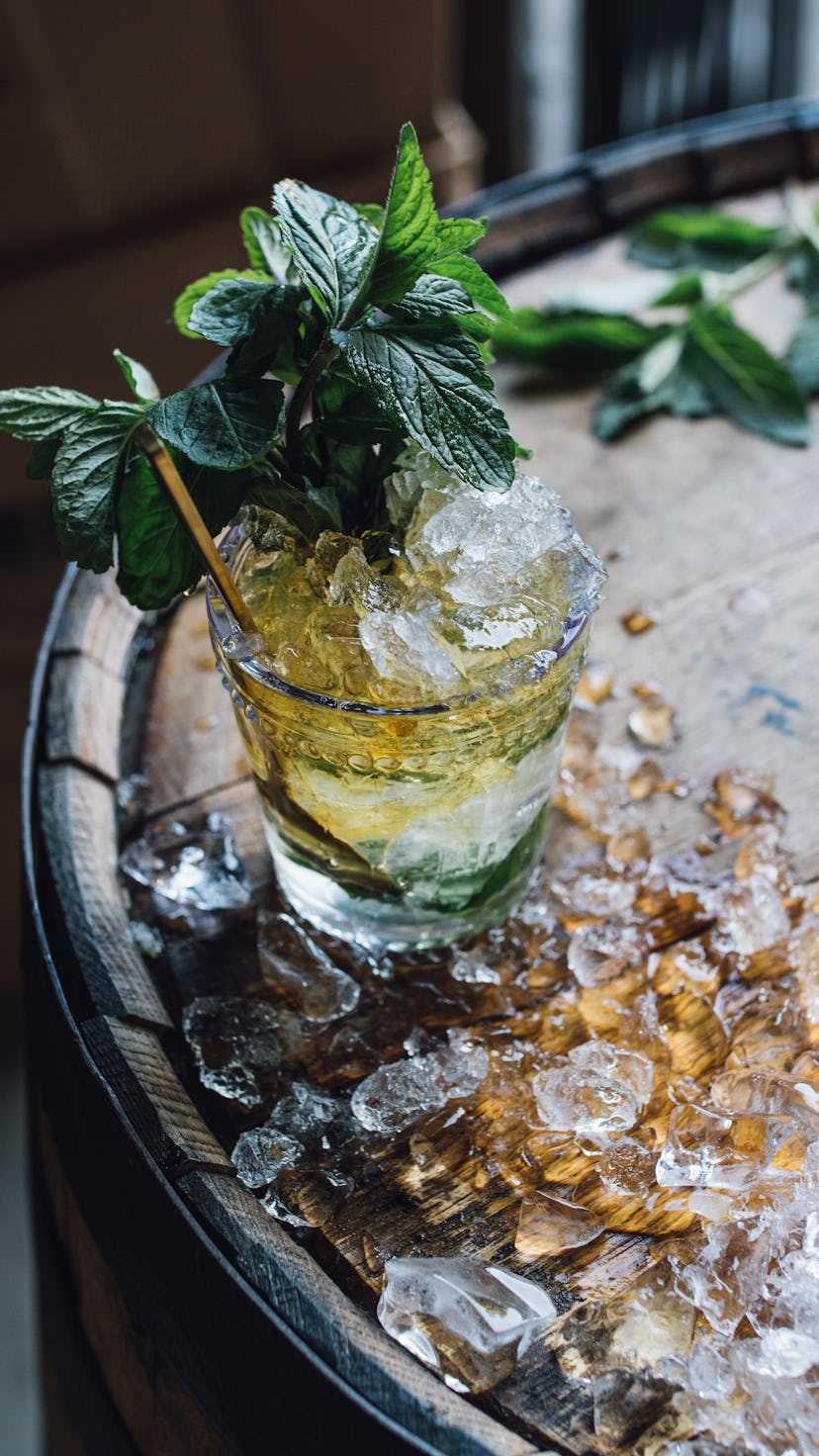 Mint Julep cocktail in glass on Bourbon whiskey barrel with crushed ice 