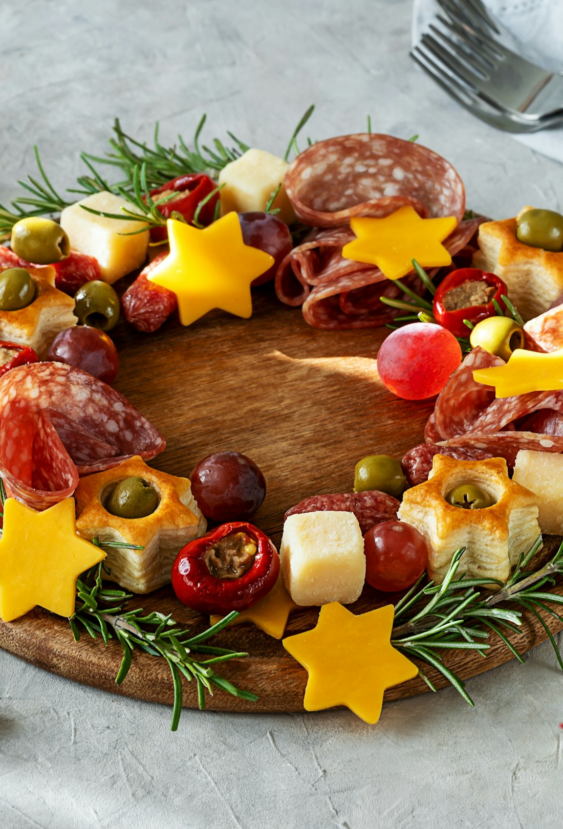 Christmas appetizers wreath on wooden board and grey background, star of Christmas plant or Poinsett...