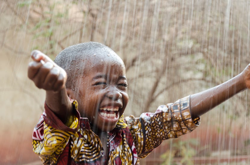 A little boy smiles in the rain. Boy names that mean love include Rudo.