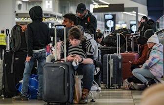 Southwest Airlines passengers sit with their luggage in the check-in area during delays and cancella...