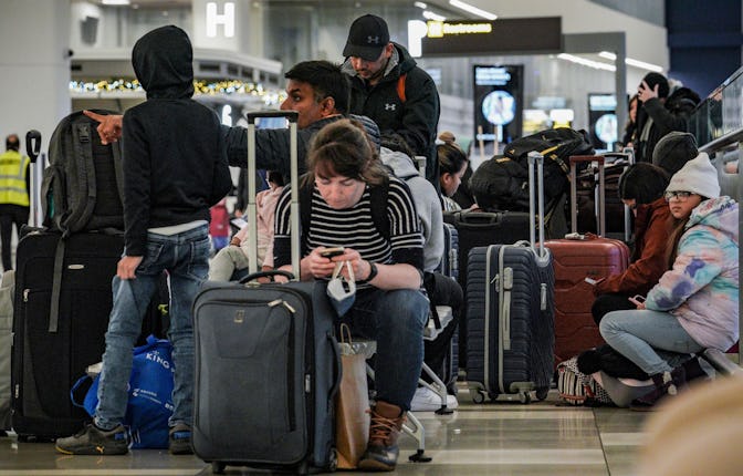 Southwest Airlines passengers sit with their luggage in the check-in area during delays and cancella...
