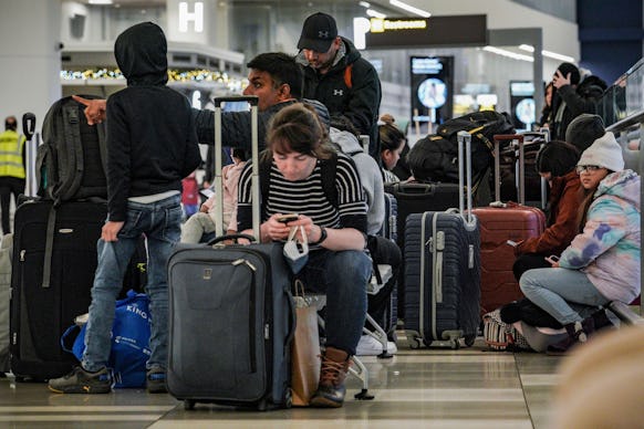 Southwest Airlines passengers sit with their luggage in the check-in area during delays and cancella...