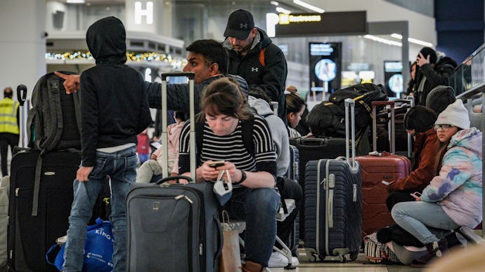 Southwest Airlines passengers sit with their luggage in the check-in area during delays and cancella...