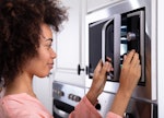 Close-up Of A Smiling Young Woman making a microwave recipe from TikTok in her dorm room.