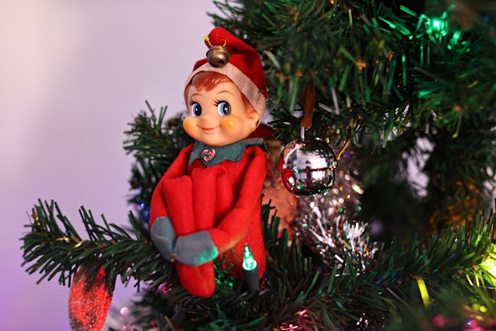 A knee hugger elf watching from the Christmas tree