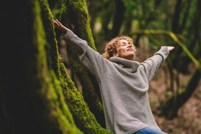 happy woman in a forest because she read her Taurus horoscope 2023