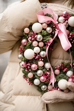 cropped photo of Christmas wreath of fir branches decorated with pink glitter balls and pink dry flo...