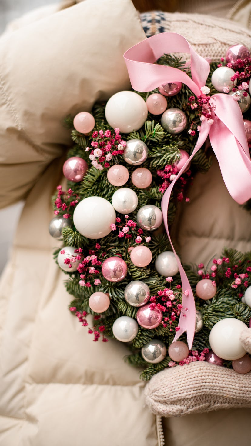 cropped photo of Christmas wreath of fir branches decorated with pink glitter balls and pink dry flo...