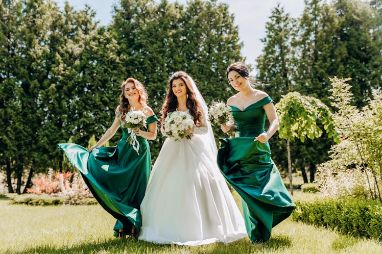 A bride and her bridesmaids show off the 2023 wedding color trends of emerald green and jewel tones....