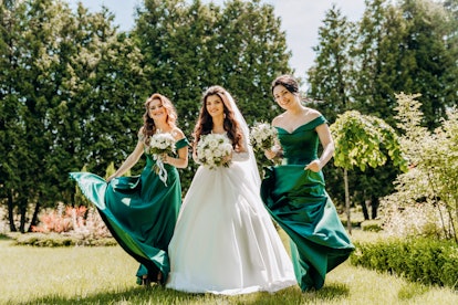A bride and her bridesmaids show off the 2023 wedding color trends of emerald green and jewel tones....