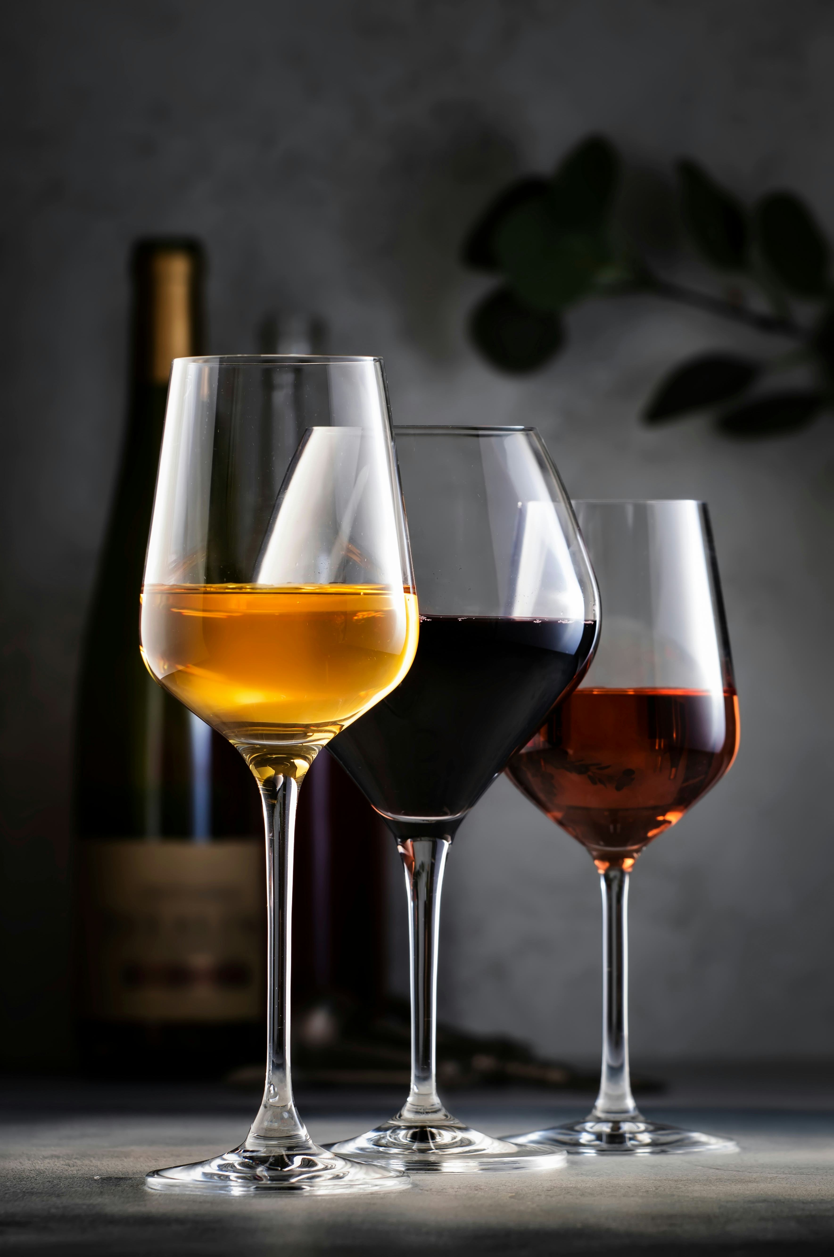 Wines assortment. Red, white, rose wine in glasses and bottles on gray table background. Wine bar, s...