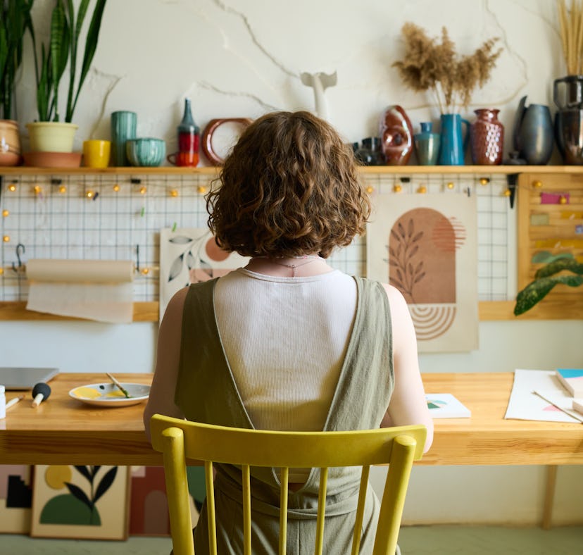 A woman decorates her room using 2023 Gen Z Home Decor Trends, Aesthetics, And Inspiration from expe...