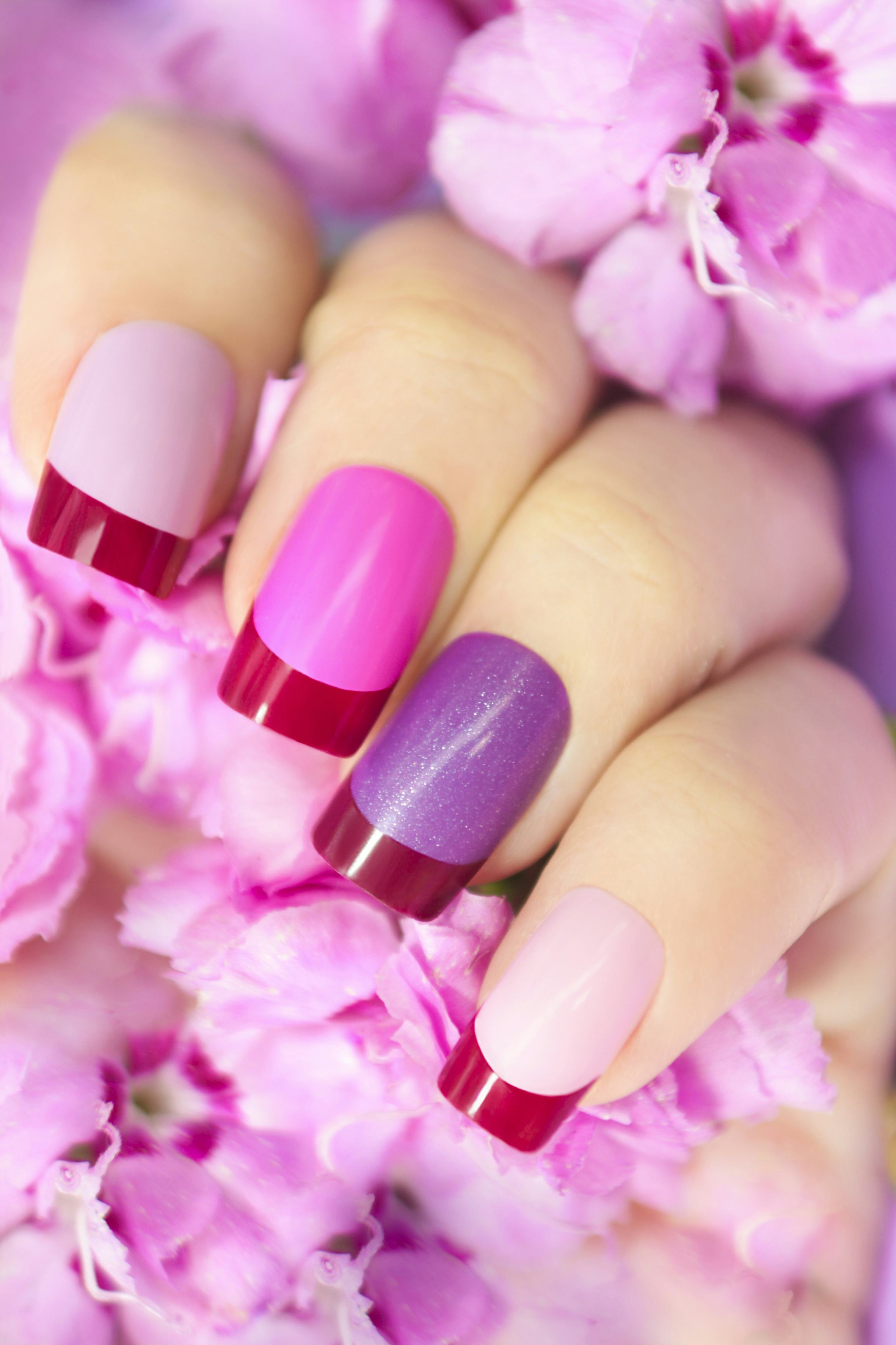 Maroon pink multicolored French manicure with flowers in hand.