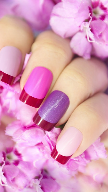 Maroon pink multicolored French manicure with flowers in hand.