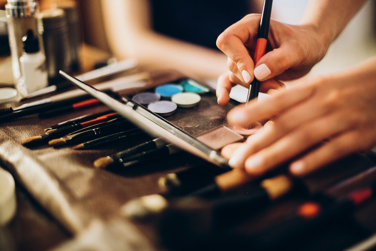 hands holding brush and eyeshadow palette. makeup artist making gorgeous make-up for bride in the mo...