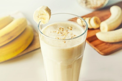 Homemade banana smoothie with oat flakes on white background. Close up. Selective focus.