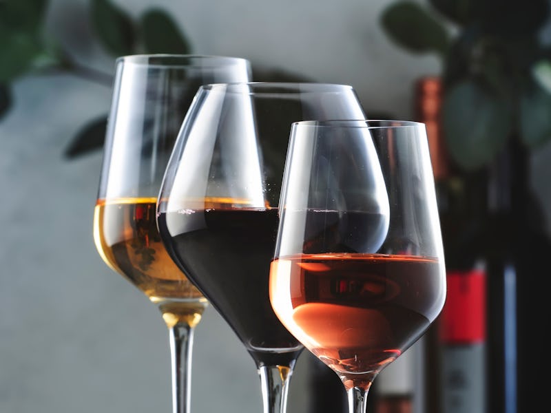 Wines assortment. Red, white, rose wine in wineglasses and bottles on gray background. Wine bar, sho...