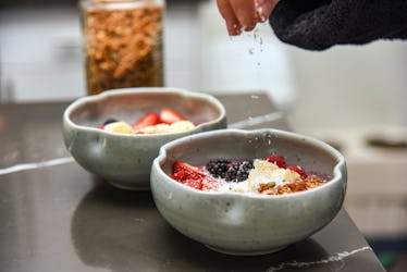 Woman’s hand sprinkling coconut shavings as part of a baked oatmeal recipe TikTok.